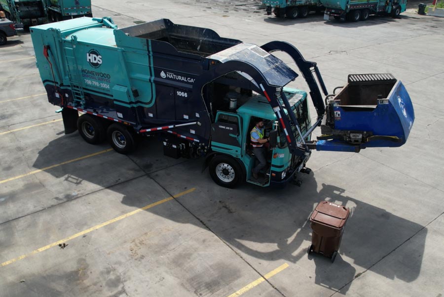 garbage truck lifts waste over cab