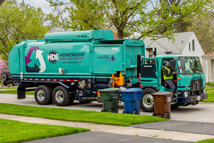 garbage truck on street with recycle can and garbage cans